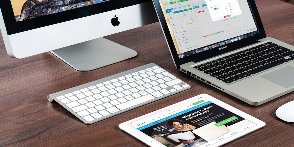 Apple tablet, laptop, and desktop computer on wooden desk