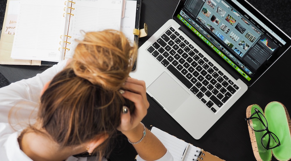 Woman with hands on her head annoyed at computer